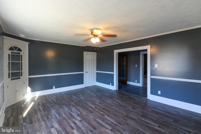 empty room with ceiling fan, dark wood-type flooring, and crown molding