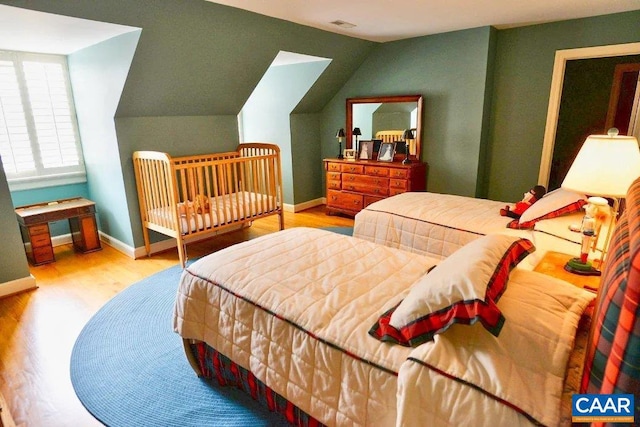 bedroom with vaulted ceiling and light wood-type flooring