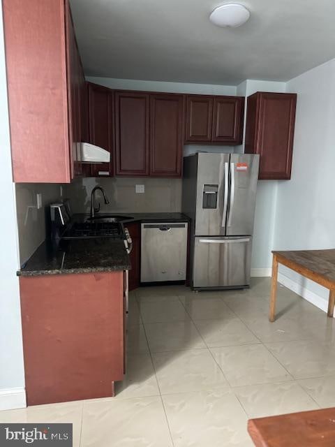 kitchen with dark stone counters, light tile floors, appliances with stainless steel finishes, and sink