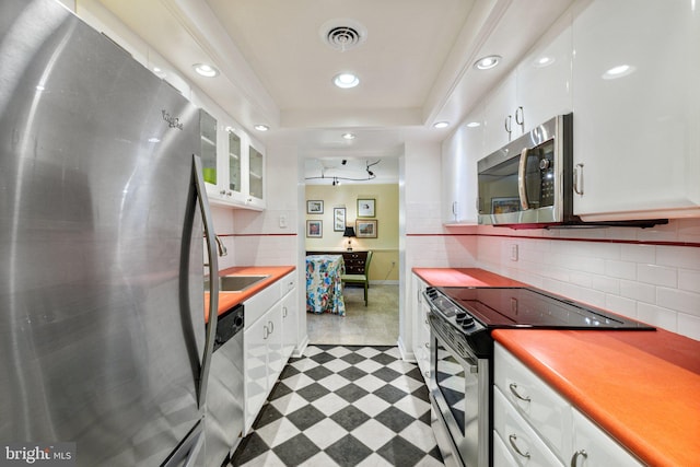 kitchen with white cabinetry, appliances with stainless steel finishes, light tile flooring, and tasteful backsplash