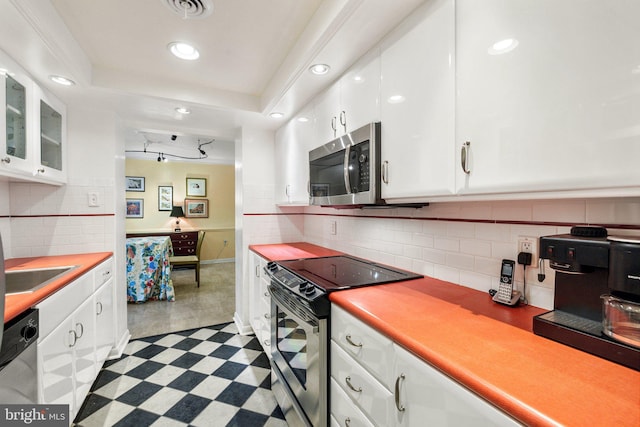 kitchen featuring appliances with stainless steel finishes, backsplash, white cabinetry, and light tile floors