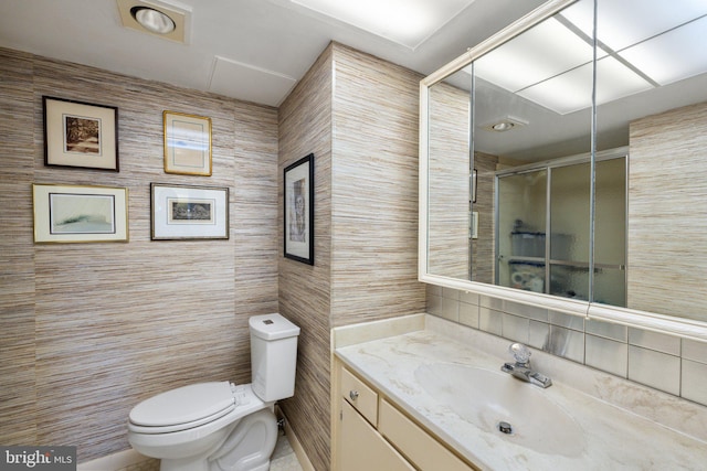 bathroom featuring tile walls, toilet, vanity, and an enclosed shower