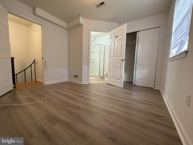 unfurnished bedroom featuring connected bathroom, a closet, and dark wood-type flooring