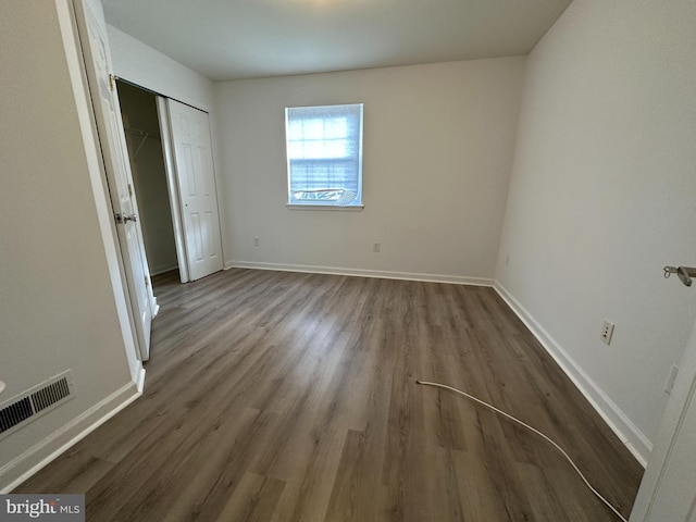 unfurnished bedroom with dark hardwood / wood-style flooring and a closet