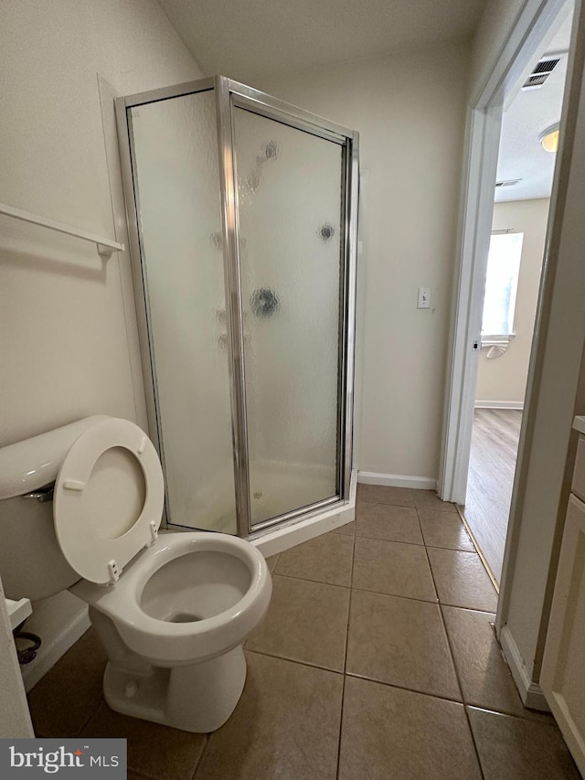 bathroom with an enclosed shower, toilet, and tile floors