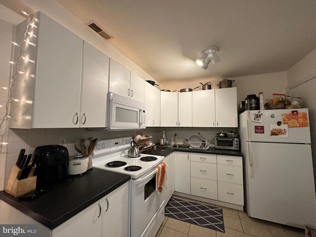 kitchen with light tile flooring, tasteful backsplash, white appliances, sink, and white cabinets