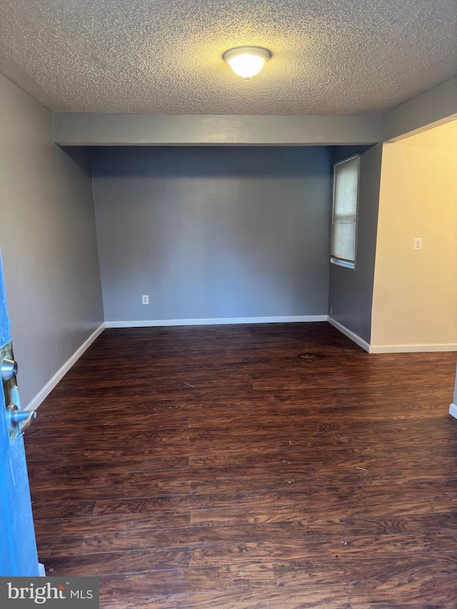 empty room with a textured ceiling and dark wood-type flooring