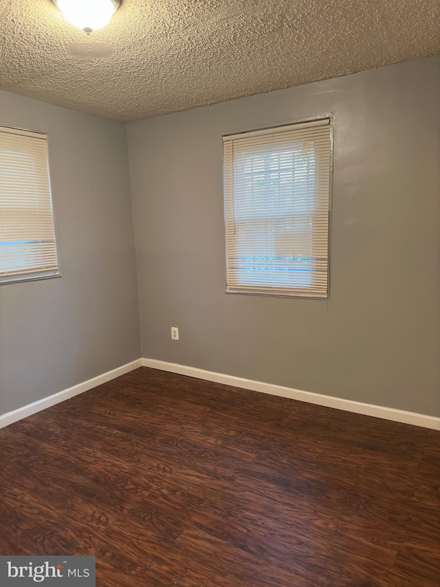 spare room with a textured ceiling and dark hardwood / wood-style floors