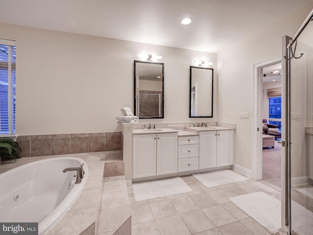 bathroom featuring a relaxing tiled bath, tile floors, and dual bowl vanity