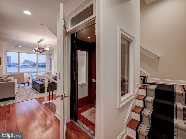 staircase featuring a chandelier, a water view, and hardwood / wood-style flooring