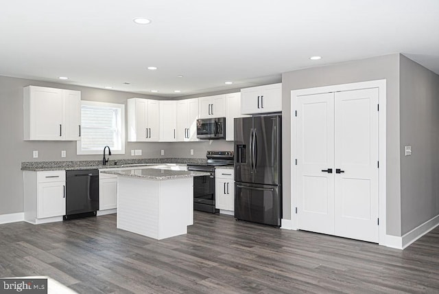 kitchen featuring dark wood-type flooring, white cabinetry, a center island, black appliances, and light stone countertops