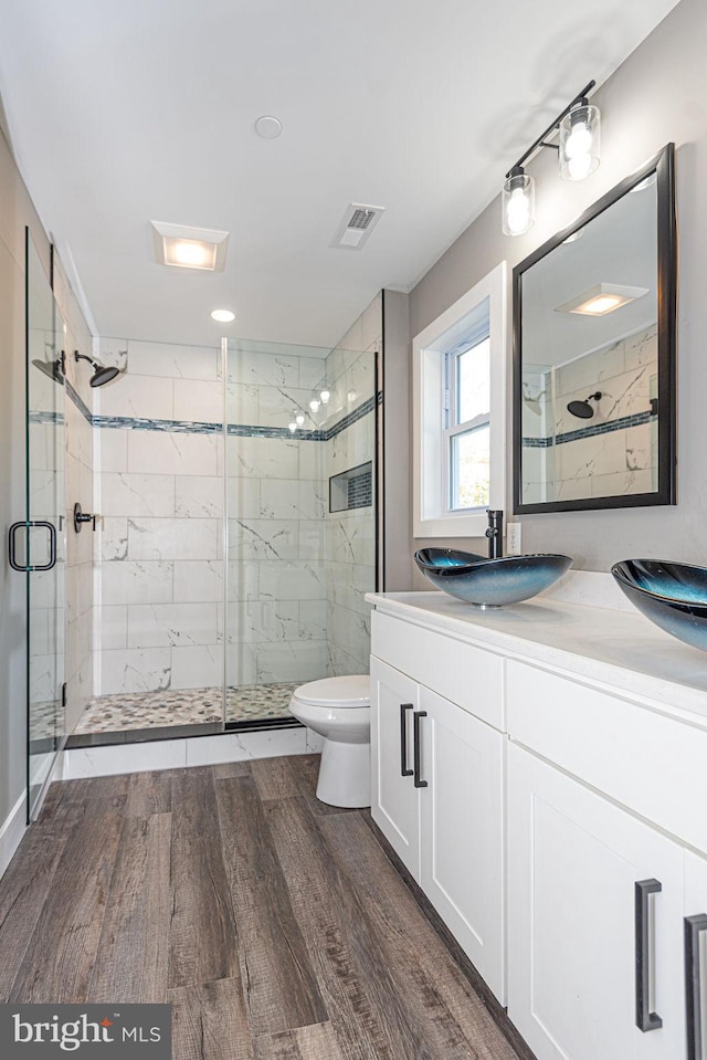 bathroom featuring toilet, hardwood / wood-style flooring, an enclosed shower, and vanity with extensive cabinet space