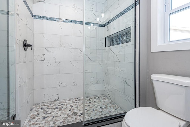 bathroom featuring a shower with shower door and toilet