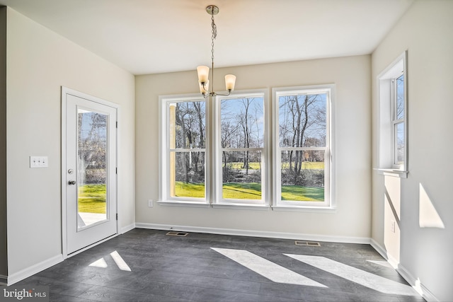 unfurnished dining area with a notable chandelier and dark wood-type flooring