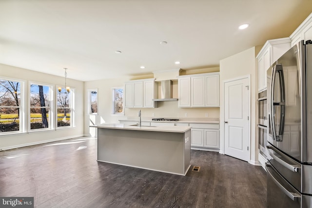 kitchen with white cabinetry, wall chimney range hood, an island with sink, and stainless steel appliances