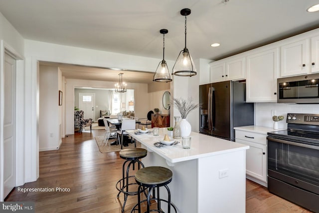 kitchen featuring appliances with stainless steel finishes, a center island, white cabinetry, and pendant lighting