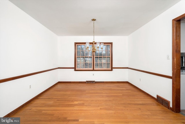 unfurnished dining area with a notable chandelier and light hardwood / wood-style floors