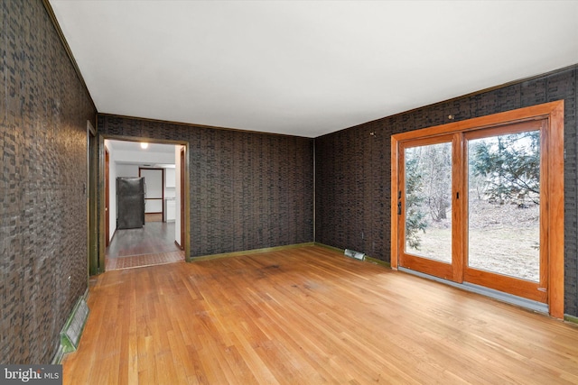 unfurnished room with brick wall and light wood-type flooring