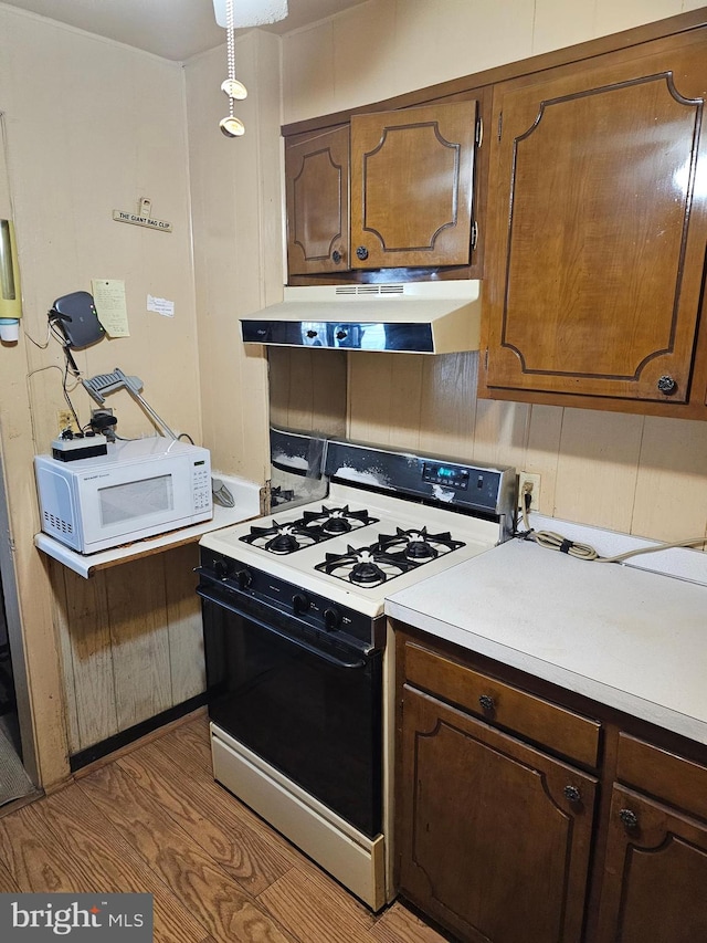 kitchen with pendant lighting, white appliances, dark hardwood / wood-style floors, and fume extractor