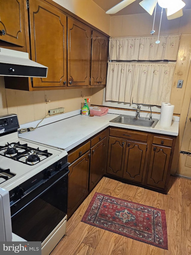 kitchen with sink, ceiling fan, white range with gas cooktop, and light wood-type flooring