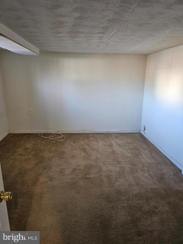 empty room with dark carpet and a textured ceiling