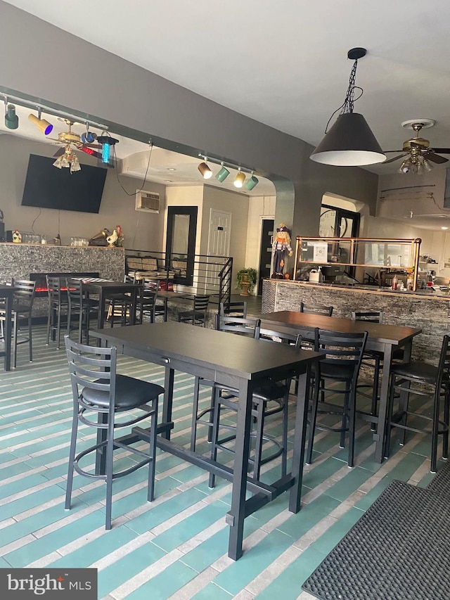 dining space with a wall mounted AC and ceiling fan