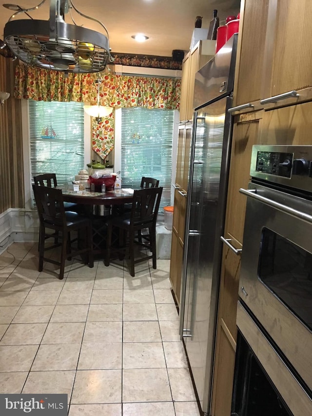 kitchen with wall oven, oven, and light tile floors