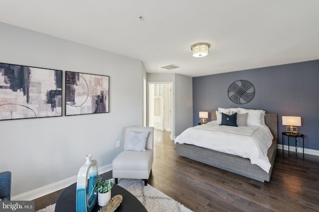 bedroom with dark wood-type flooring and connected bathroom