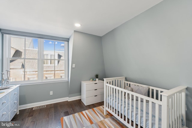 bedroom with a nursery area and dark hardwood / wood-style flooring