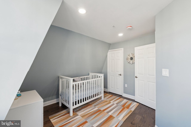 bedroom featuring hardwood / wood-style flooring and a crib