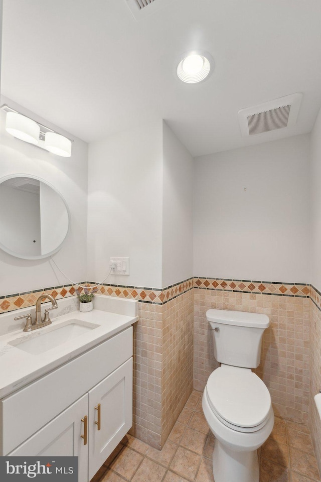 bathroom with vanity, toilet, and tile walls