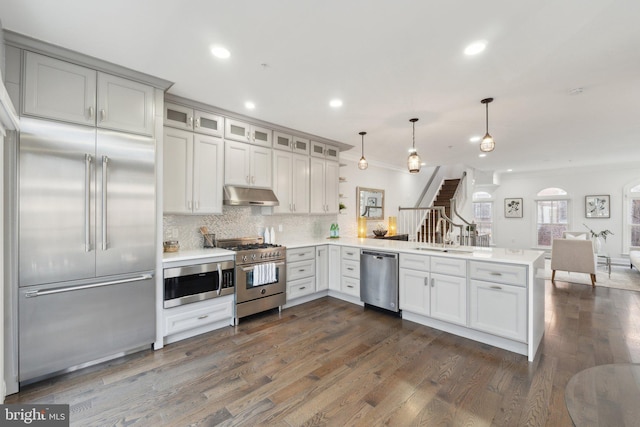 kitchen with high quality appliances, pendant lighting, backsplash, and kitchen peninsula