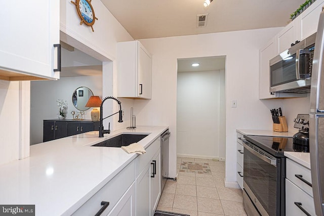 kitchen featuring stainless steel appliances, white cabinets, light tile floors, and sink