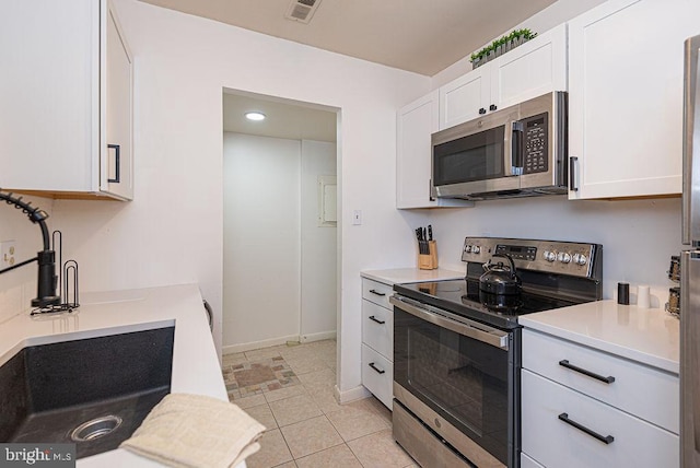 kitchen featuring white cabinets, light tile flooring, and appliances with stainless steel finishes