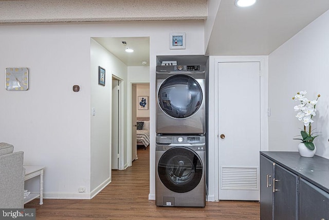 laundry room with dark hardwood / wood-style flooring and stacked washer and dryer