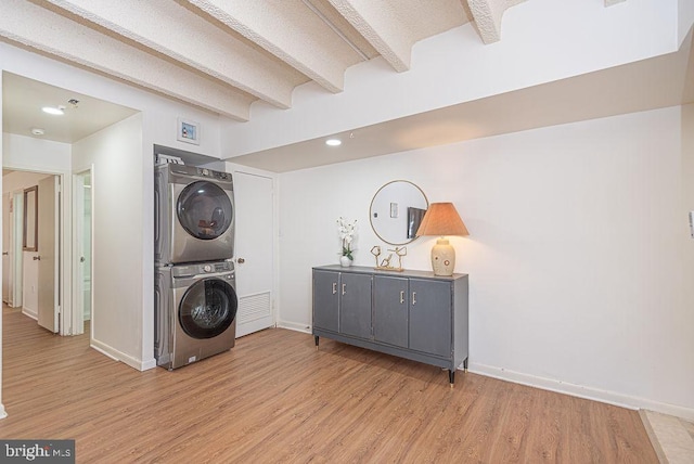 clothes washing area with stacked washing maching and dryer and light wood-type flooring