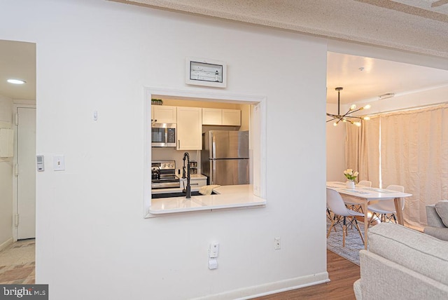 kitchen featuring stainless steel appliances, hardwood / wood-style flooring, a chandelier, and a textured ceiling