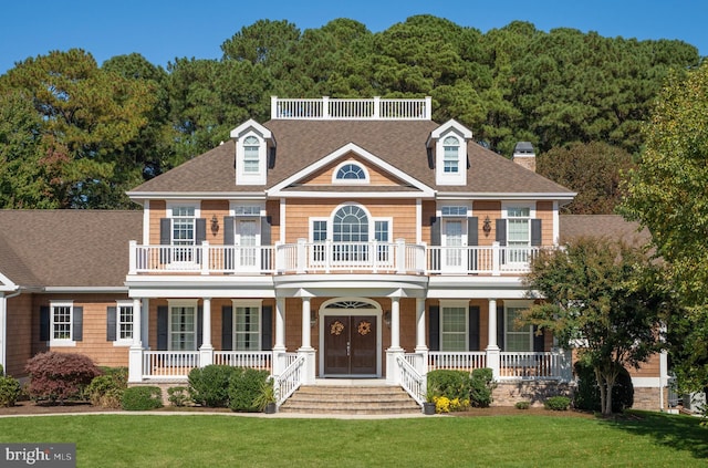 colonial inspired home featuring a balcony, a porch, and a front lawn