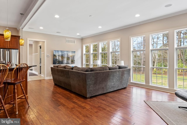 living room featuring plenty of natural light, ornamental molding, and dark wood-type flooring