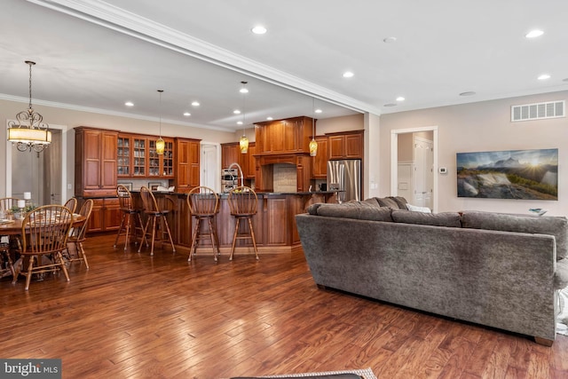 living room featuring a chandelier, crown molding, and dark hardwood / wood-style flooring