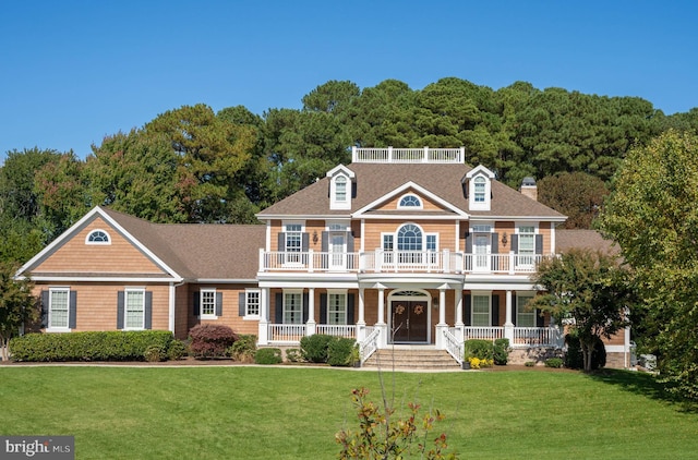 colonial house featuring a balcony, covered porch, and a front lawn