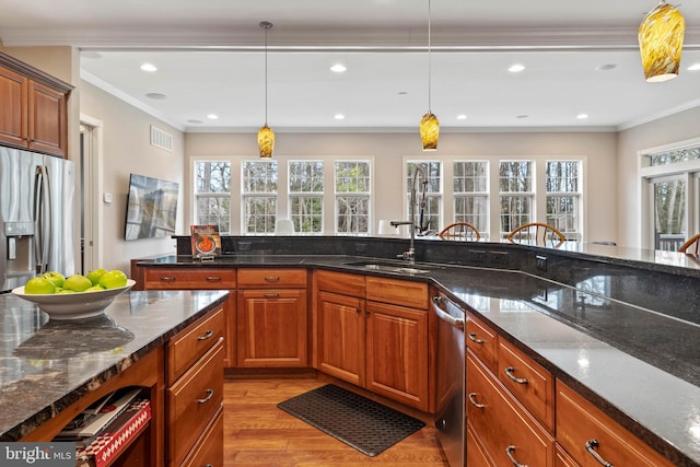 kitchen featuring appliances with stainless steel finishes, dark stone countertops, light hardwood / wood-style floors, and pendant lighting