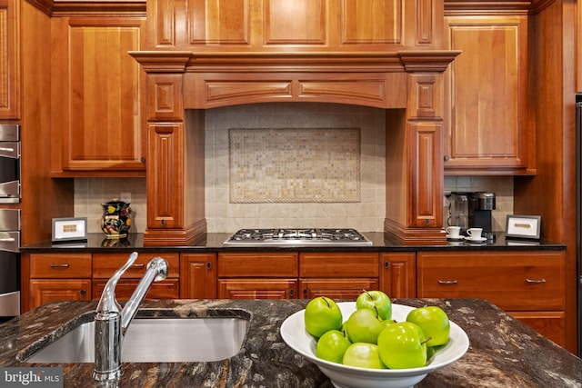 kitchen with dark stone counters, backsplash, sink, and stainless steel appliances