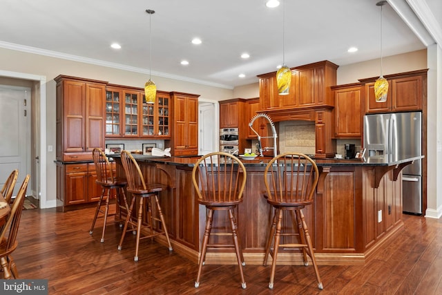 kitchen featuring dark hardwood / wood-style flooring, decorative light fixtures, a kitchen island with sink, and a breakfast bar