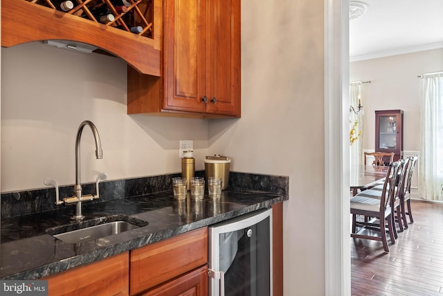 kitchen featuring wood-type flooring, sink, wine cooler, dark stone counters, and ornamental molding