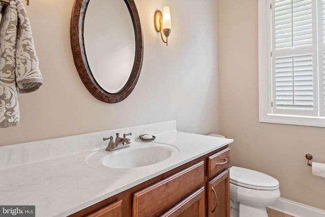 bathroom with toilet, vanity, and a healthy amount of sunlight