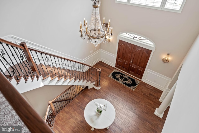 foyer entrance with a chandelier, a towering ceiling, dark hardwood / wood-style floors, and a wealth of natural light