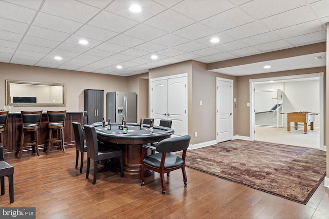 dining room featuring a paneled ceiling, bar area, and dark hardwood / wood-style floors