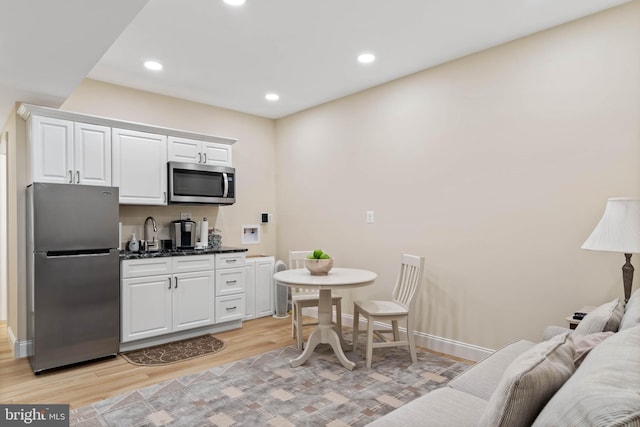 kitchen with stainless steel appliances, light wood-type flooring, and white cabinets