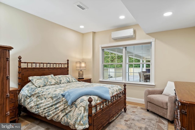 bedroom featuring light wood-type flooring and a wall unit AC